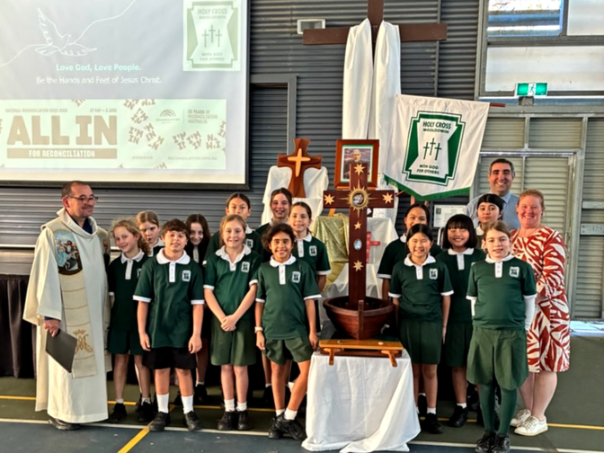 A group of students, staff and the parish priest with the Holy Migrant Cross.