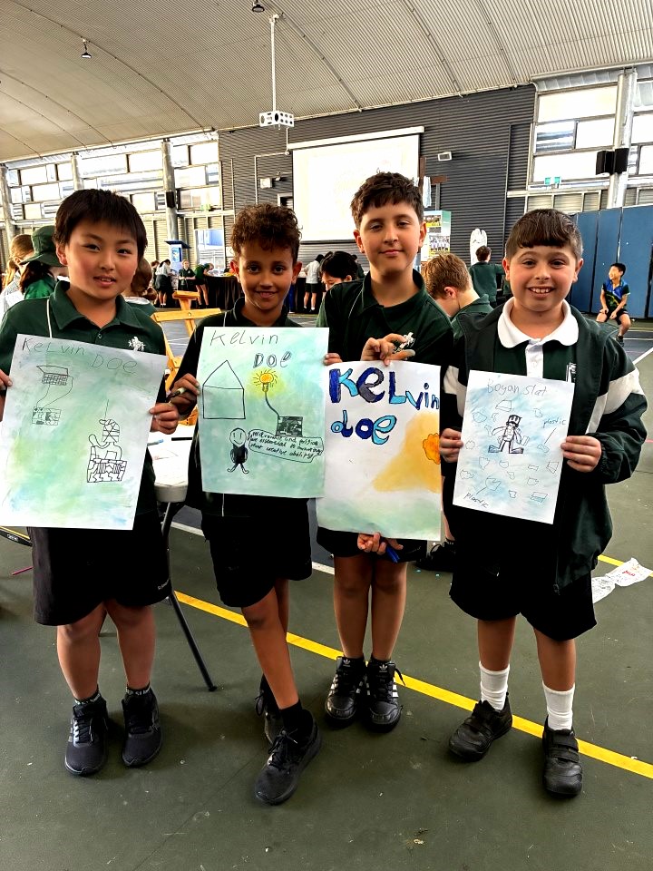 Four primary school students stand in a school hall displaying posters they created about changemakers and community action. The students share their learning as part of Mercy Formation Day activities exploring how young people can make a difference.