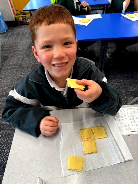 Student proudly displays fraction pieces during an engaging mathematics lesson focused on equal parts, sharing and number sense.