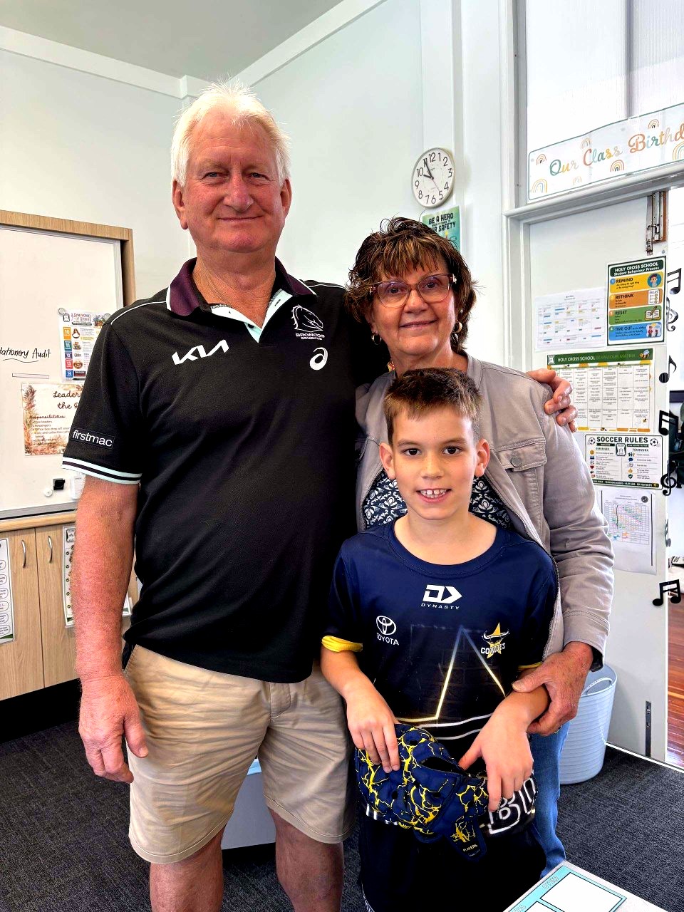 Holy Cross student poses with grandparents in a classroom, celebrating Grandparents' Day and the importance of family connections.