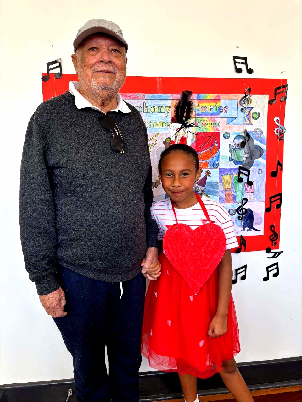 Student and grandparent stand together beside colourful Book Week artwork, celebrating learning, creativity and community at Holy Cross.